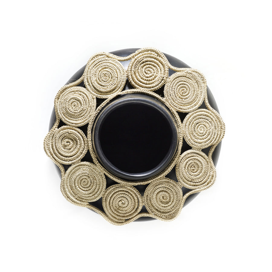 A top view of the Ames Coyar Vase 1 by Ames shows its black ceramic body with an elegant, light wickerwork rim coiled in circular patterns around the opening.