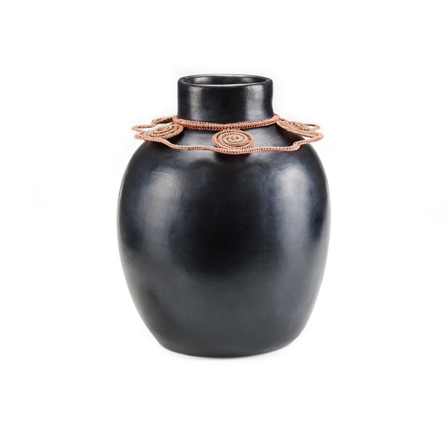The Ames Coyar Vase 2 is a smooth, black ceramic piece featuring a wide body, narrow neck, and intricate pink rosette design around the top. Its elegant charm stands out against a simple white background.