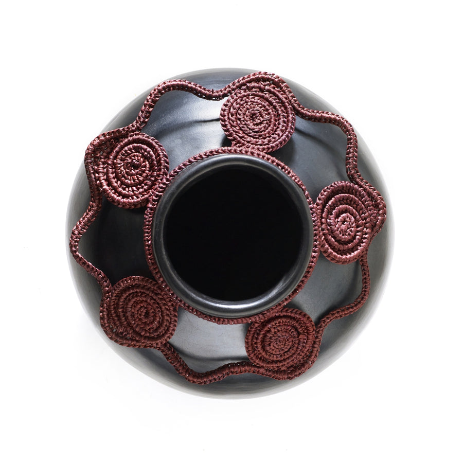 Top view of the Coyar Vase 2 by Ames, featuring a wide opening and red rope-like designs reminiscent of wickerwork. The intricate detailing contrasts beautifully with its smooth, dark finish.