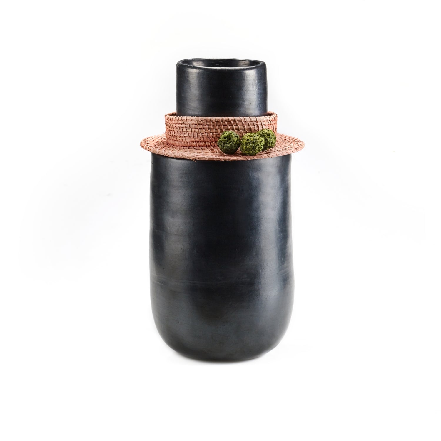 The Ames Coyar Vase 3 by Ames is a tall, smooth black ceramic vase with a wide base, narrow neck, and a woven flat light brown lid with wickerwork and two small green decorative balls. Shown on a white background.