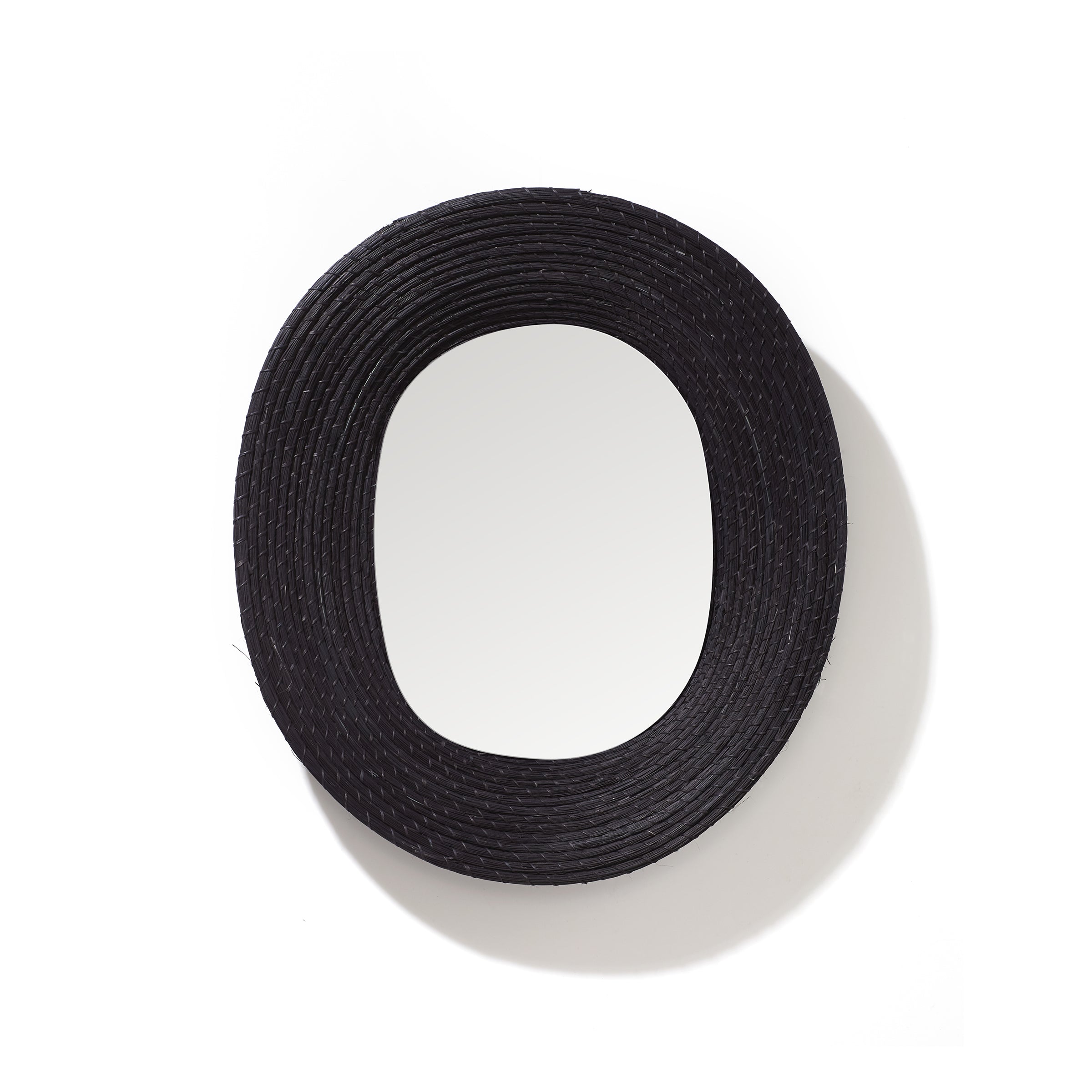 The Ames Killa Mirror by Ames is a round wall mirror featuring a thick, textured black frame handmade from Iraca palm, shown against a plain white background.