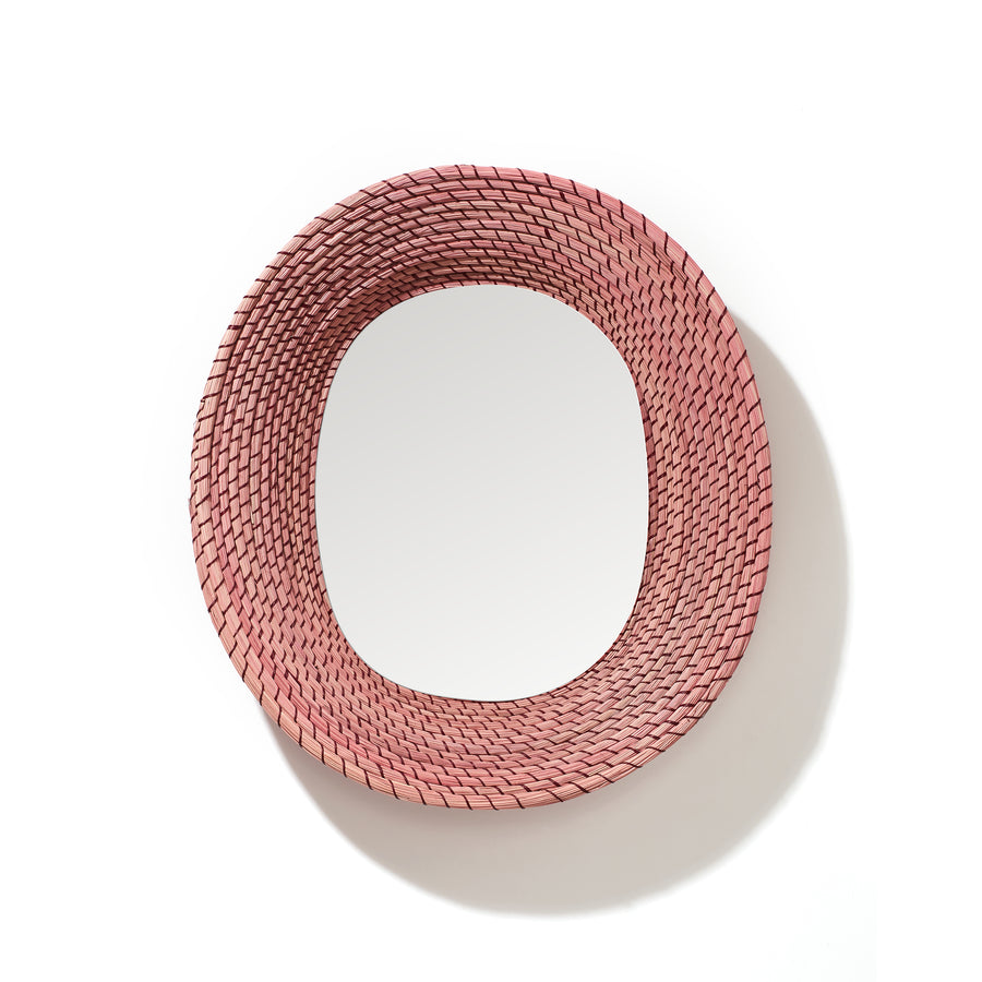 The Ames Killa Mirror by Ames features a round glass center framed by thick, handmade woven pink iraca palm, giving it a textured, basket-like look. Displayed on a white background.