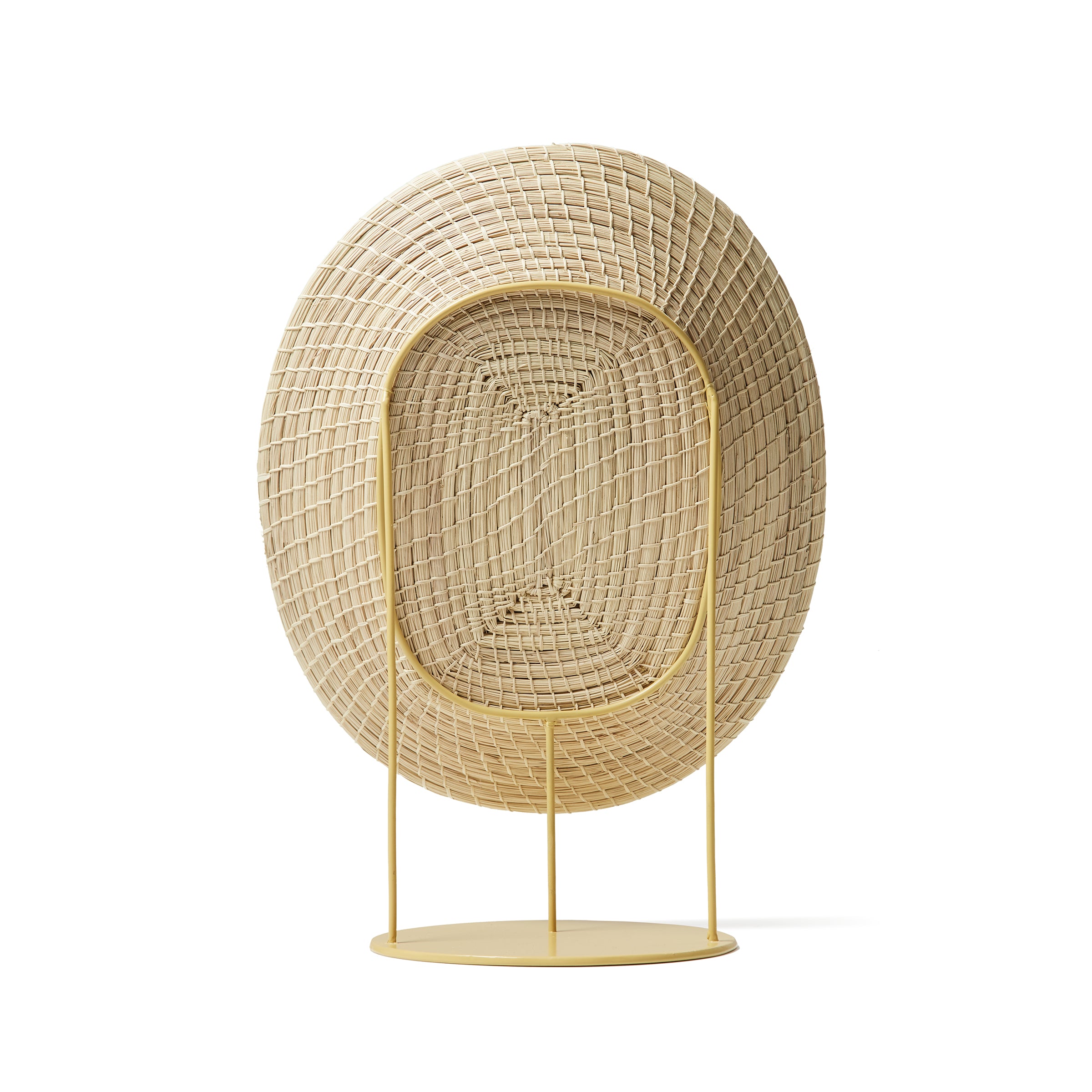 The Ames Killa Standing Mirror by Ames features a large, woven oval frame in light beige, inspired by handmade basket artistry. Supported by a minimalist yellow metal stand and circular base reminiscent of Pauline Deltour’s iconic designs.