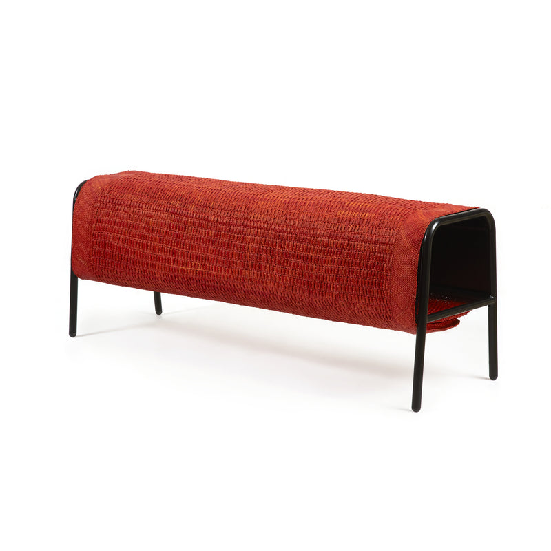 The Ames Mecato Bench by Ames features a red woven iraca palm seat and black powder-coated steel legs in a sleek, minimalist design.