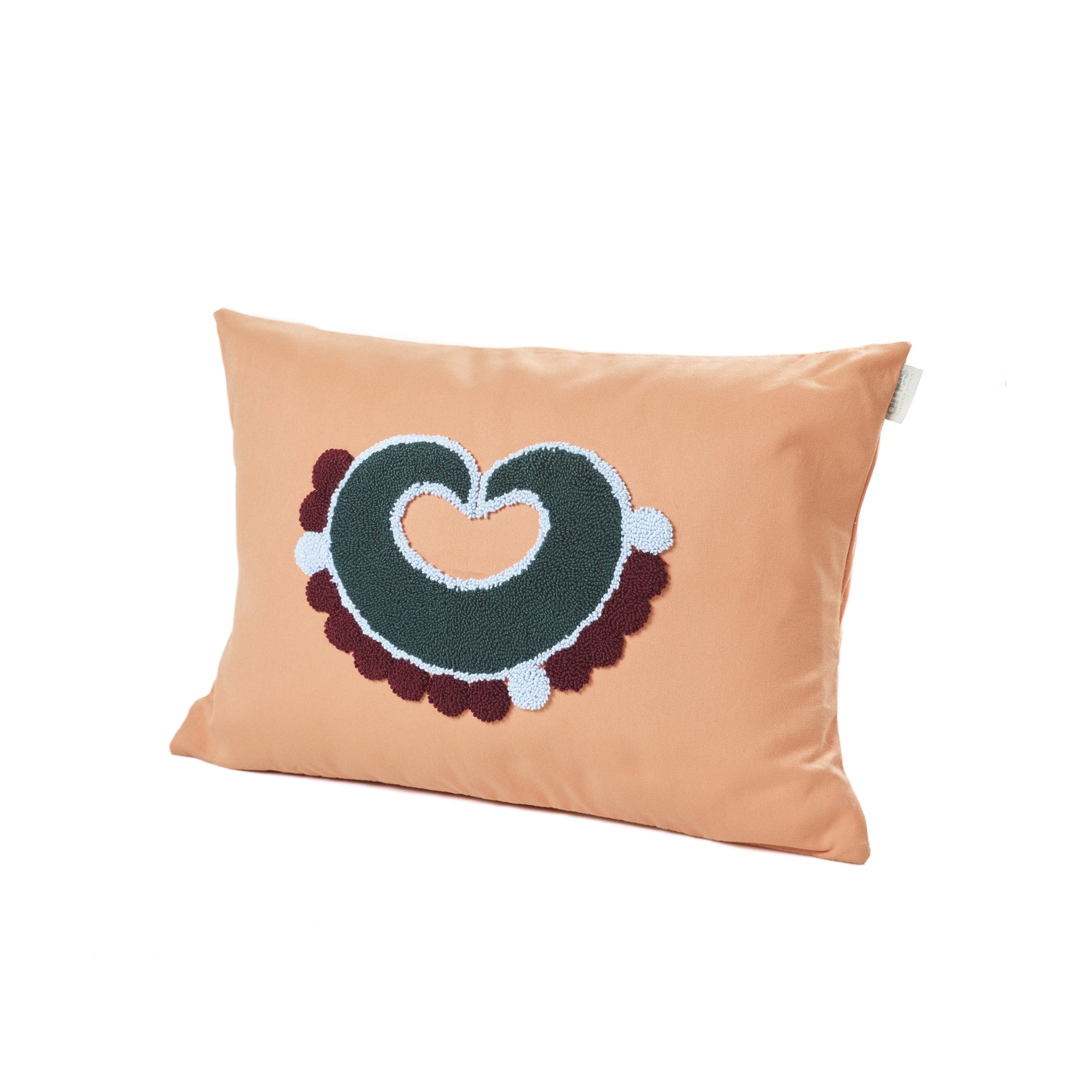 The Ames Nido Piqui is a smooth, rectangular orange pillow with an abstract embroidered design in green, white, and dark red. Reminiscent of Sebastian Herkners Nido Collection, it showcases a stylized heart shape and modern appeal.