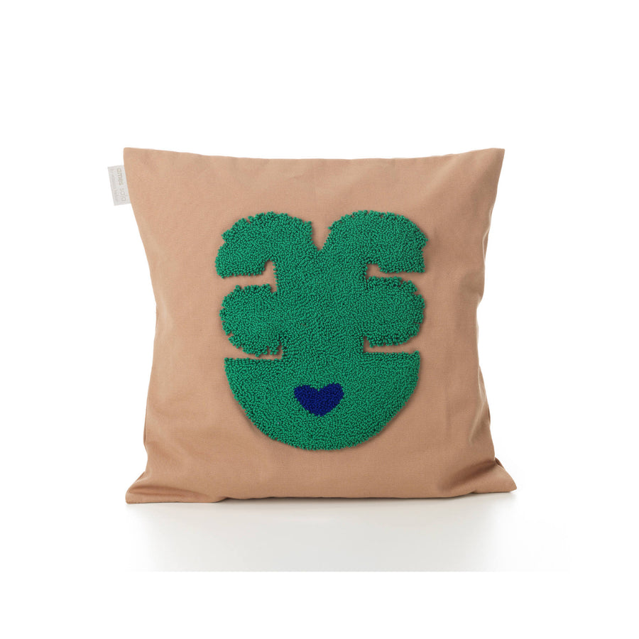 As part of the exclusive Ames Nido Qeztal collection, this handmade square cushion features a beige cover with a textured green abstract face design, whimsically decorated with a small blue heart at the bottom.
