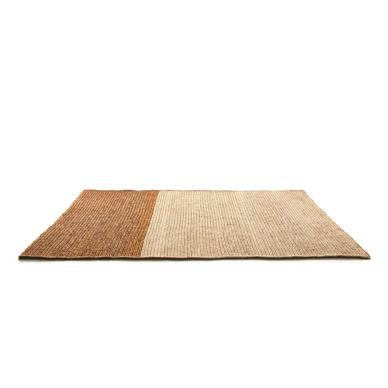 The Ames Par Rug by Ames is a handmade rectangular woven rug crafted from natural fibers. It features two sections—warm brown and light beige—in a minimalistic design, ideal for those seeking unique, artisan rugs.