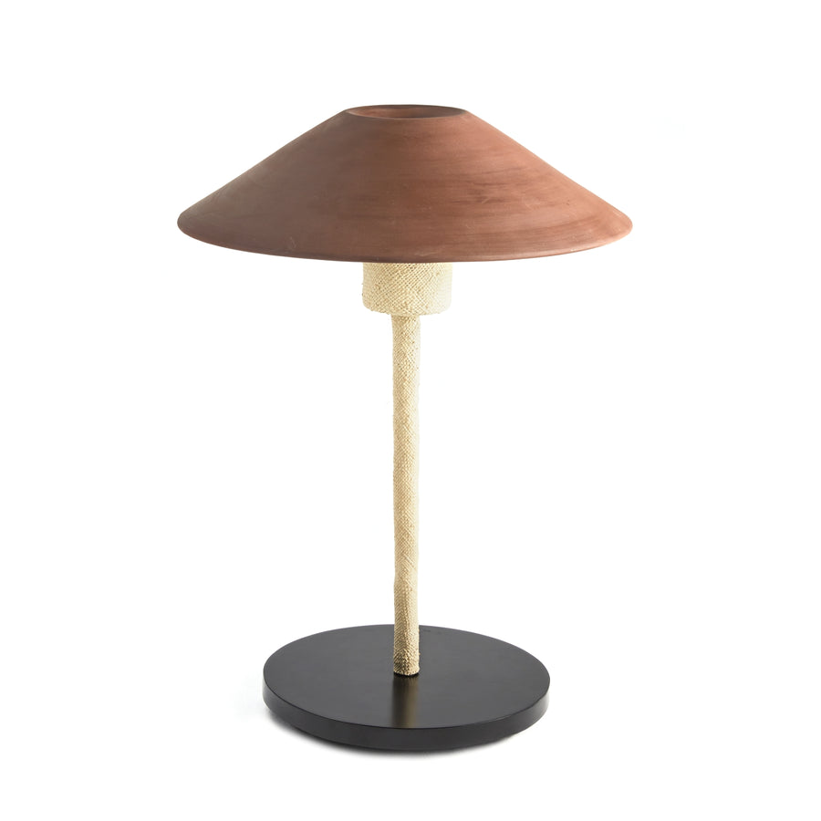 The Raiz Table Lamp by Ames showcases a conical brown shade inspired by Colombian craftsmanship, a textured beige stem, and a round black base, blending earthy and modern elements.