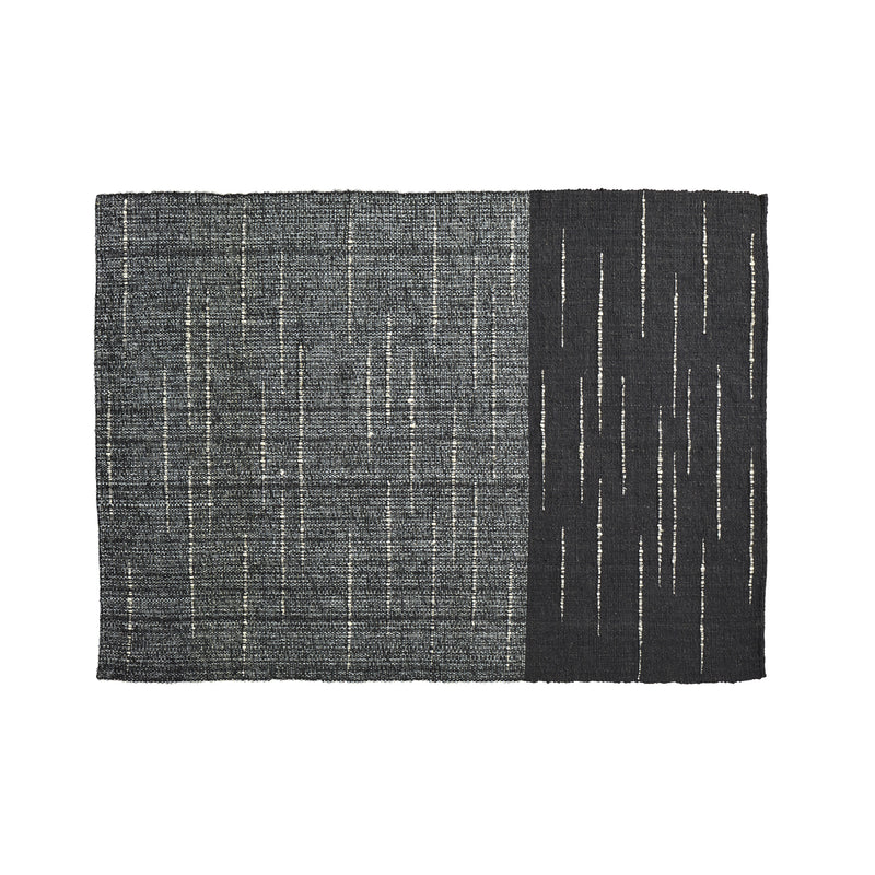 The Ames Subas Rug by Ames is a rectangular wool rug with a dark, speckled gray left side and solid black right side, both accented by thin, irregular vertical white lines in a scattered pattern.