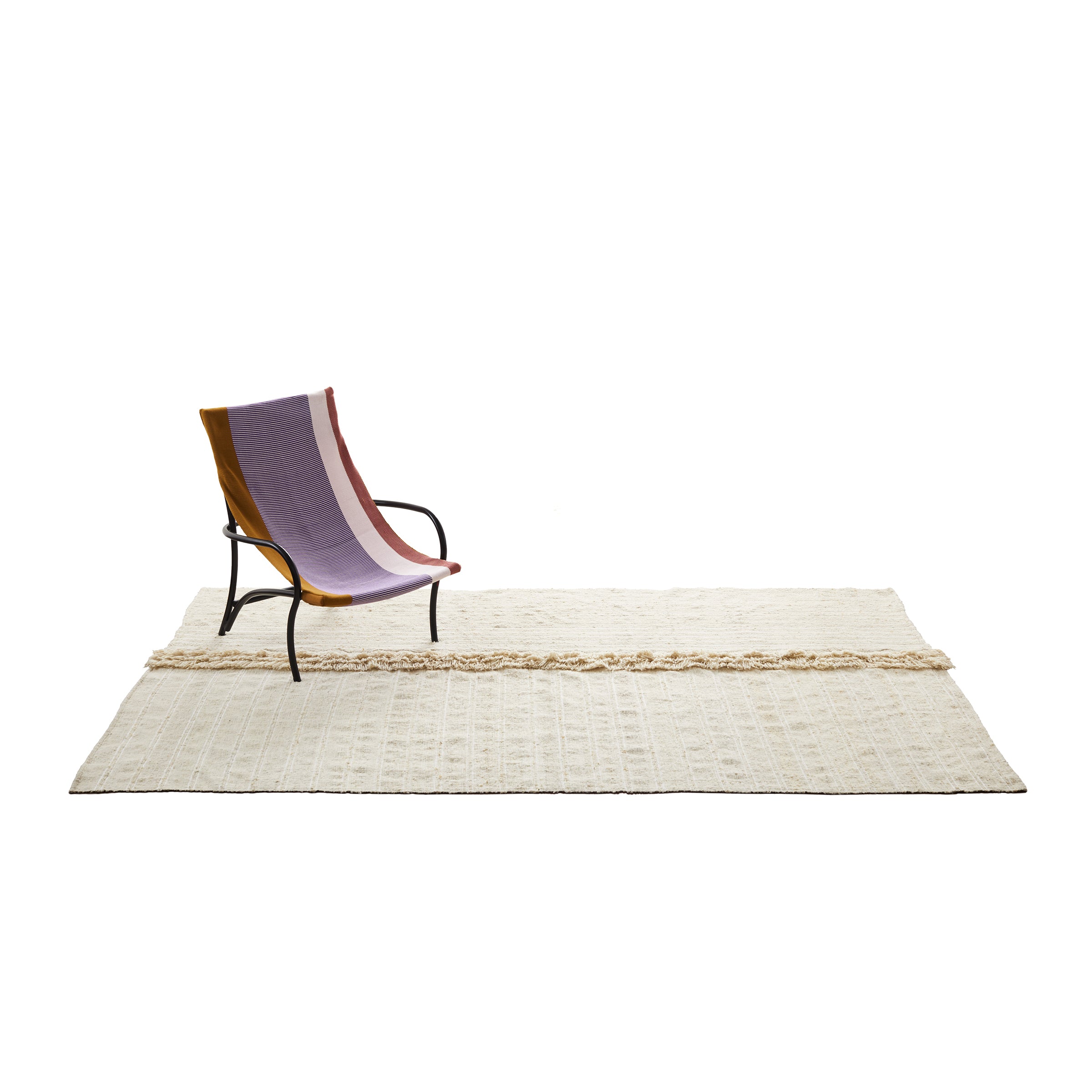 A modern chair with a purple and brown fabric sling seat stands on the large, textured Ames Subas Rug by Ames, designed by Sebastian Herkner, set against a white background.