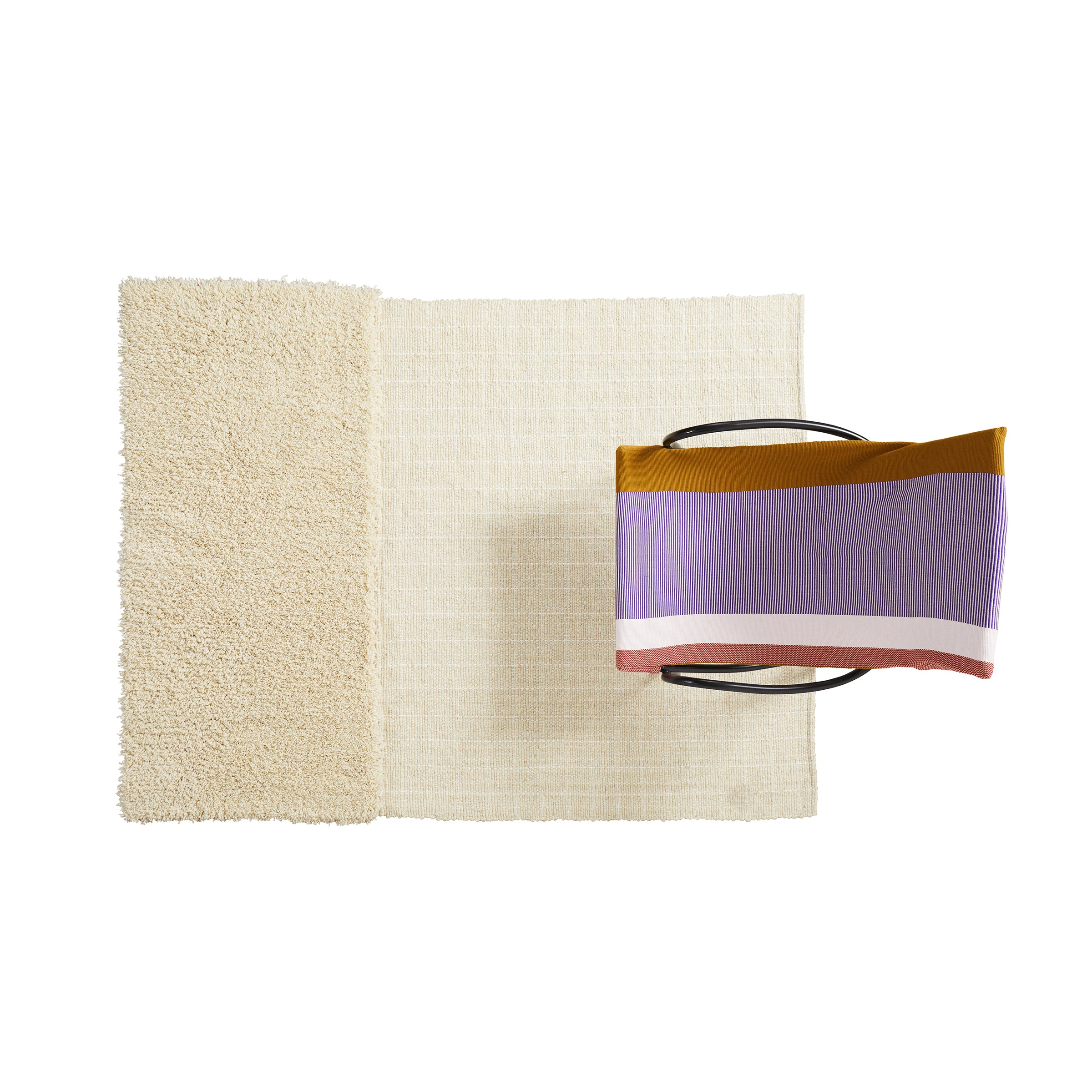 Overhead view of a modern chair with a purple, mustard yellow, and pink striped cushion, placed on two overlapping Ames Subas Rugs by Ames. The rugs are cream-colored wool on a white background. Design inspired by Sebastian Herkner.