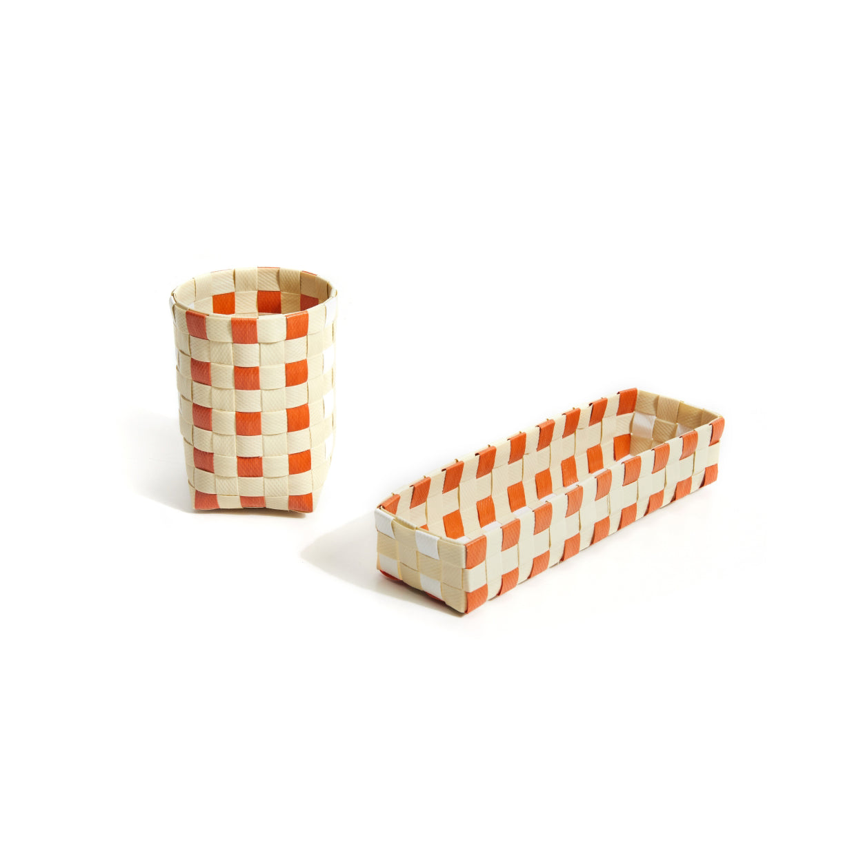 On a white background, two woven Suncho Baskets from Ames display an orange and cream checkered pattern: a cylindrical basket and a rectangular tray. Hand-crafted from recycled polypropylene, these innovative storage pieces reflect Pauline Deltours design ethos.