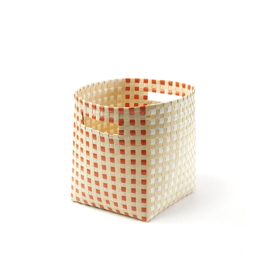 The Suncho Basket by Ames features a checkered pattern of orange and white with a convenient side handle. Crafted from recycled polypropylene, this square, woven storage piece embodies modern design and Pauline Deltours elegance against its white backdrop.