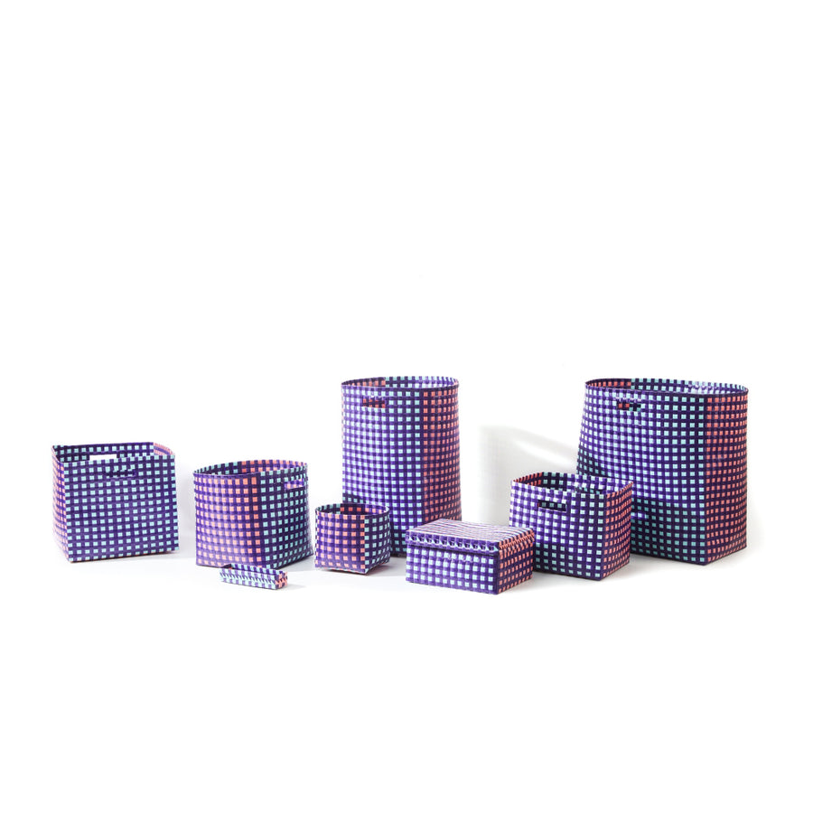 Seven Ames Suncho Baskets made from recycled polypropylene are displayed against a white background, featuring a vibrant checkered pattern in purple, pink, and white.