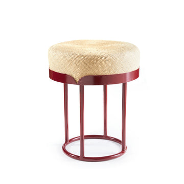 The Ames Victorias Pouf by Ames is a round stool inspired by Amazonia, featuring a woven natural-colored seat and a bold circular red metal frame with four legs joined at the base.