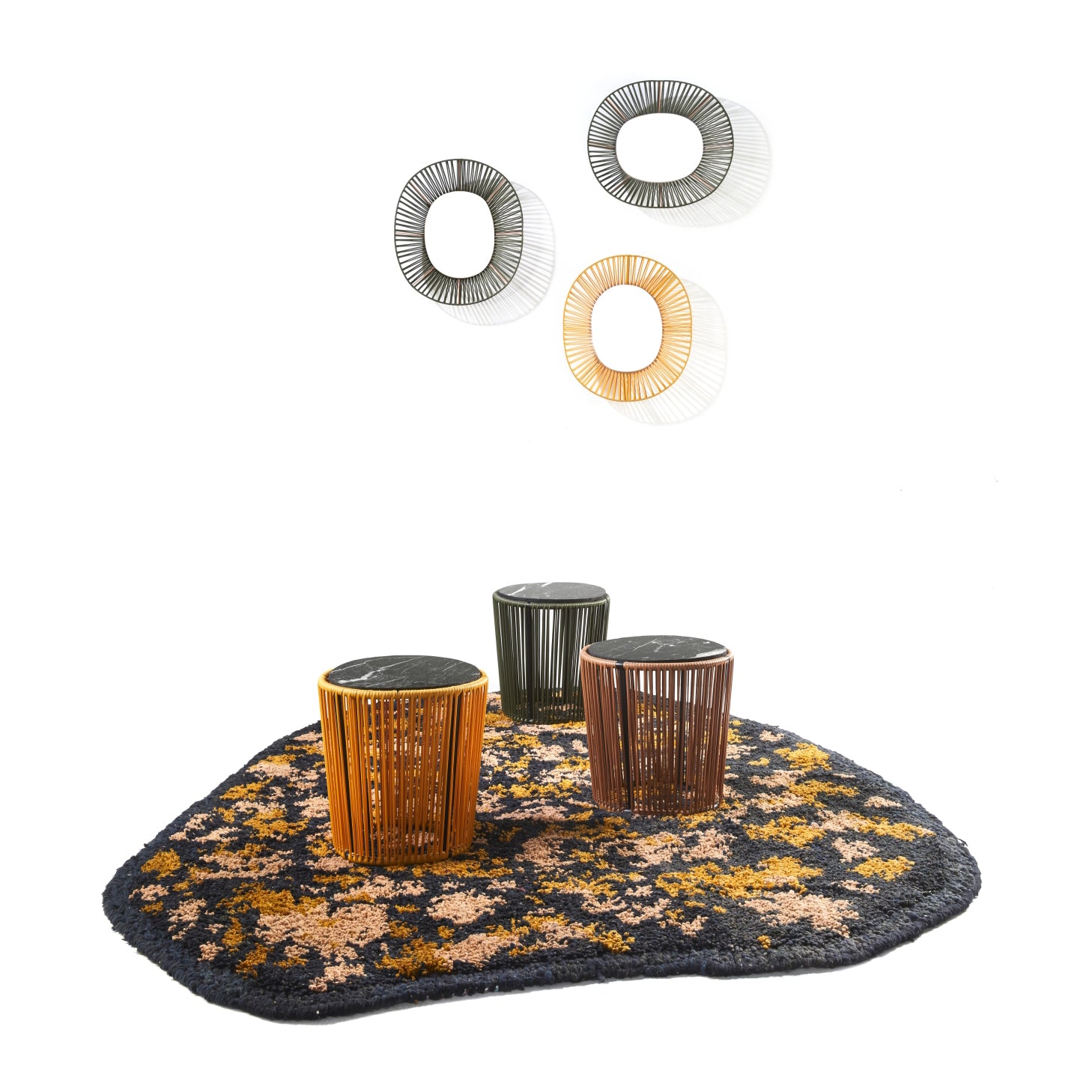 Three wire-frame side tables in yellow, green, and brown sit atop an Ames Zipa Rug by Ames, with three round wire wall decorations above them against a white background.