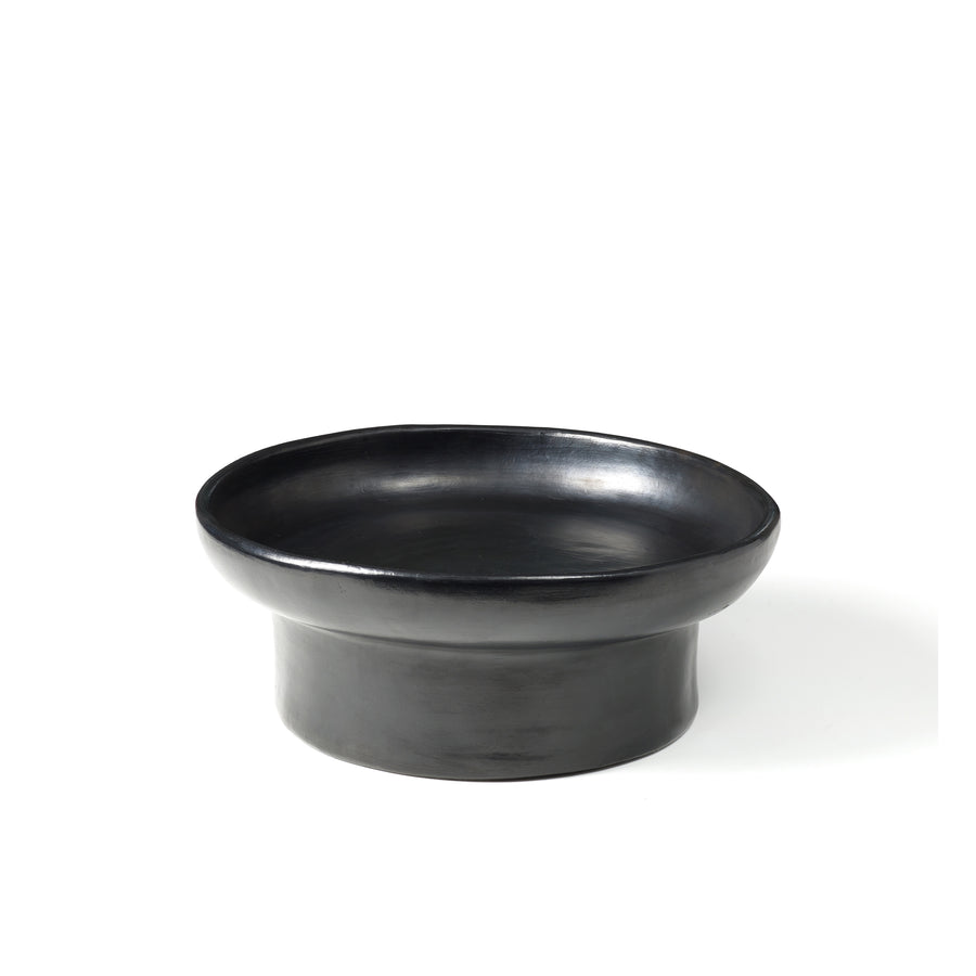 The Barro Tray 1 by Ames features a sleek, black ceramic design with a wide, shallow basin and thick cylindrical base, showcasing the artistry of Colombian manufacturing against a plain white background.