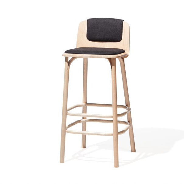 The Barstool Split by TON, designed by Arik Levy, showcases a light wood finish with a padded black seat and backrest. It has four sturdy legs with dual horizontal footrests and is elegantly displayed against a plain white background.