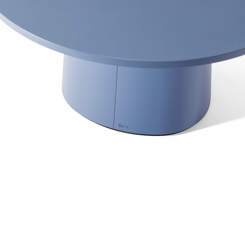 The P.O.V. Coffee Table 474/475 by TON features a round blue design with a solid cylindrical wood base against a white background. It offers various color finishes to complement any decor effortlessly.