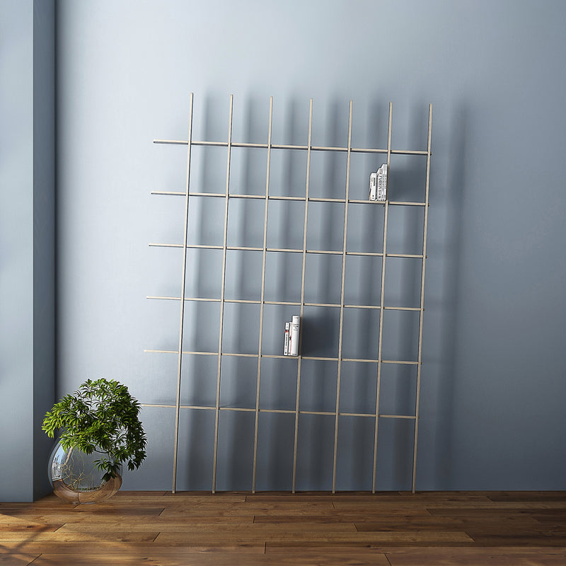 A sculptural minimalist room displays the SCHLAGSEITE grid-style metal bookshelf from Martin Breuer Bono, leaning against a light blue wall. Sparse books fill the shelves, complemented by a clear vase with green foliage on the wooden floor.