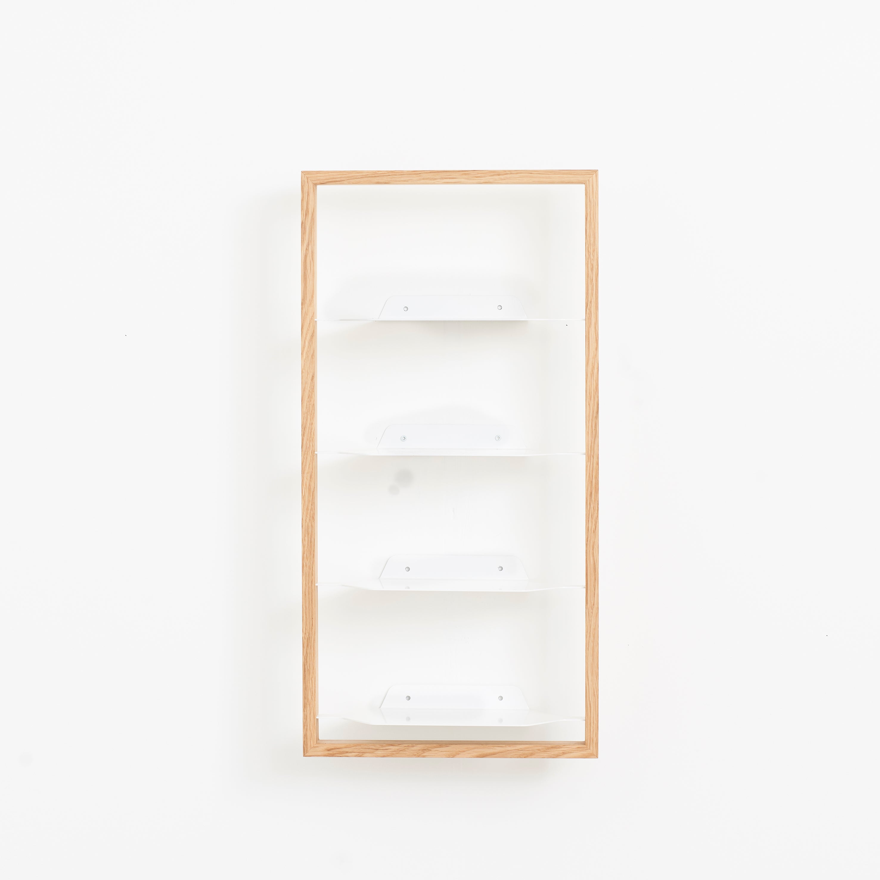 A Basti - Presentation shelf by Das kleine b with a wooden frame and four white tiers is mounted on a plain white wall, offering a minimalistic, clean design with variable size options.