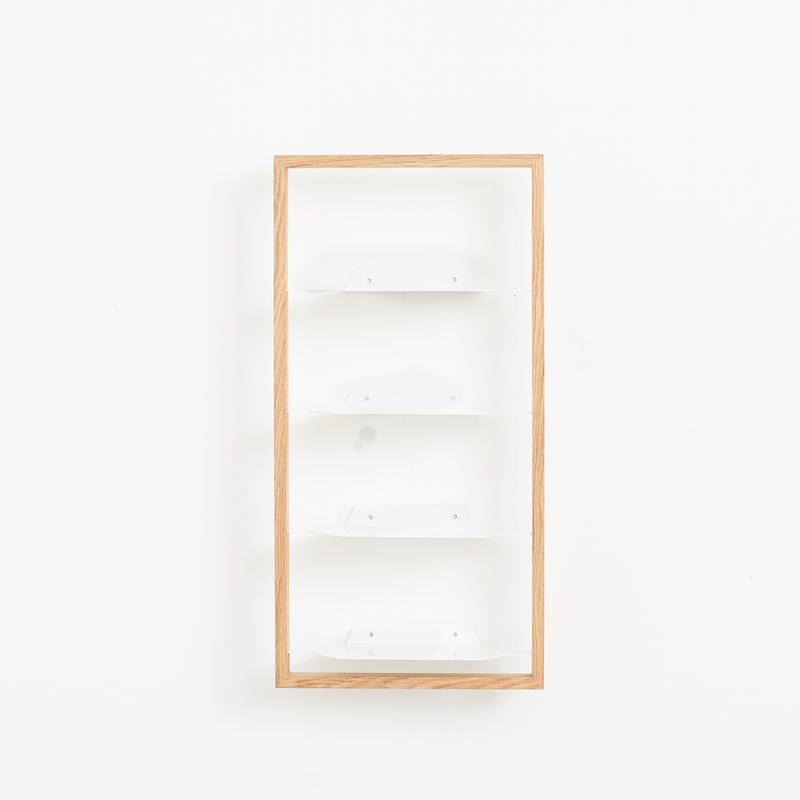 A Basti - Presentation shelf by Das kleine b with a wooden frame and four white tiers is mounted on a plain white wall, offering a minimalistic, clean design with variable size options.