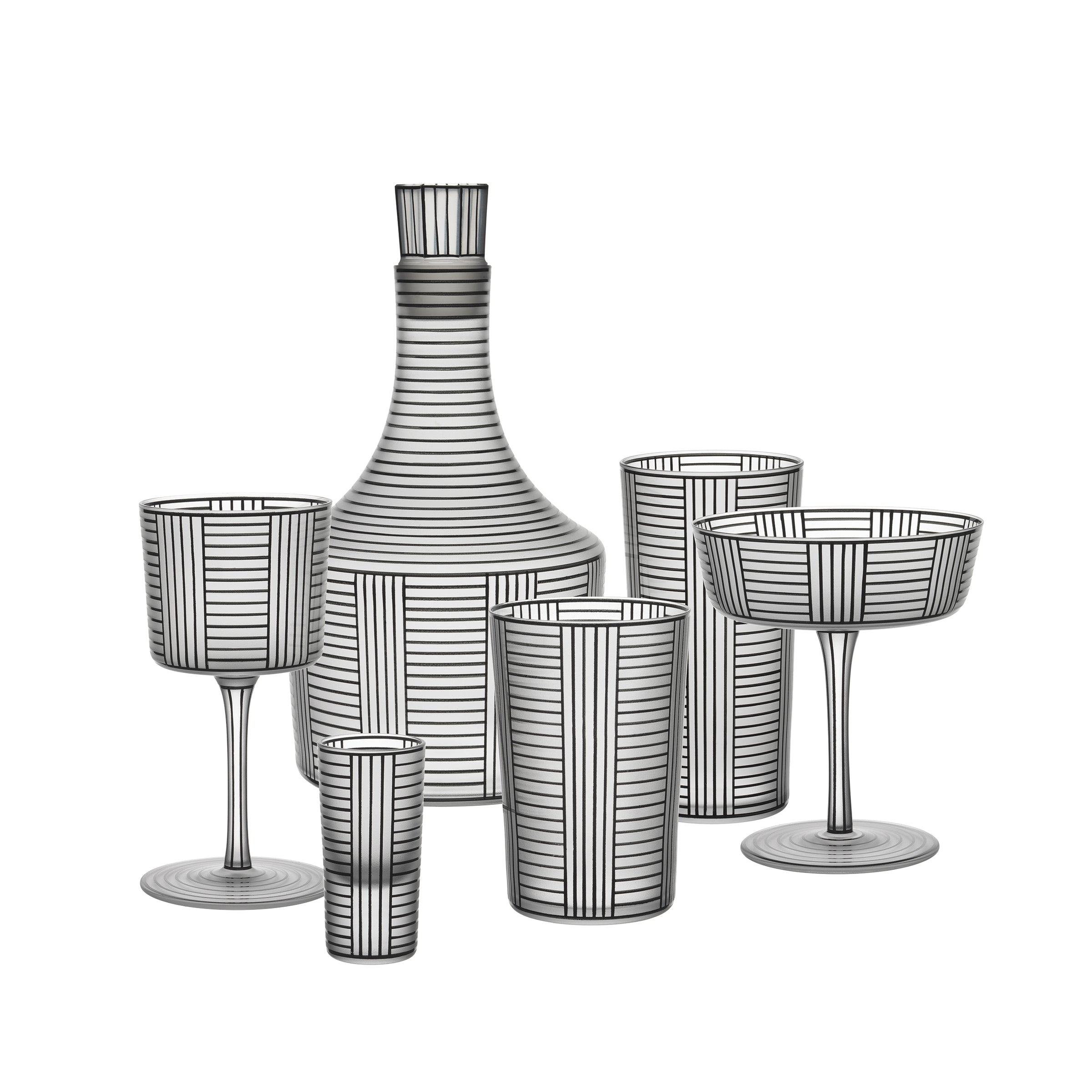 The Lobmeyr Drinking Set Serie B, inspired by Josef Hoffmanns designs, features a crystal glassware collection including a decanter, two wine glasses, a coupe glass, a tall glass, and a small tumbler with vertical and horizontal black stripes displayed against a white background.