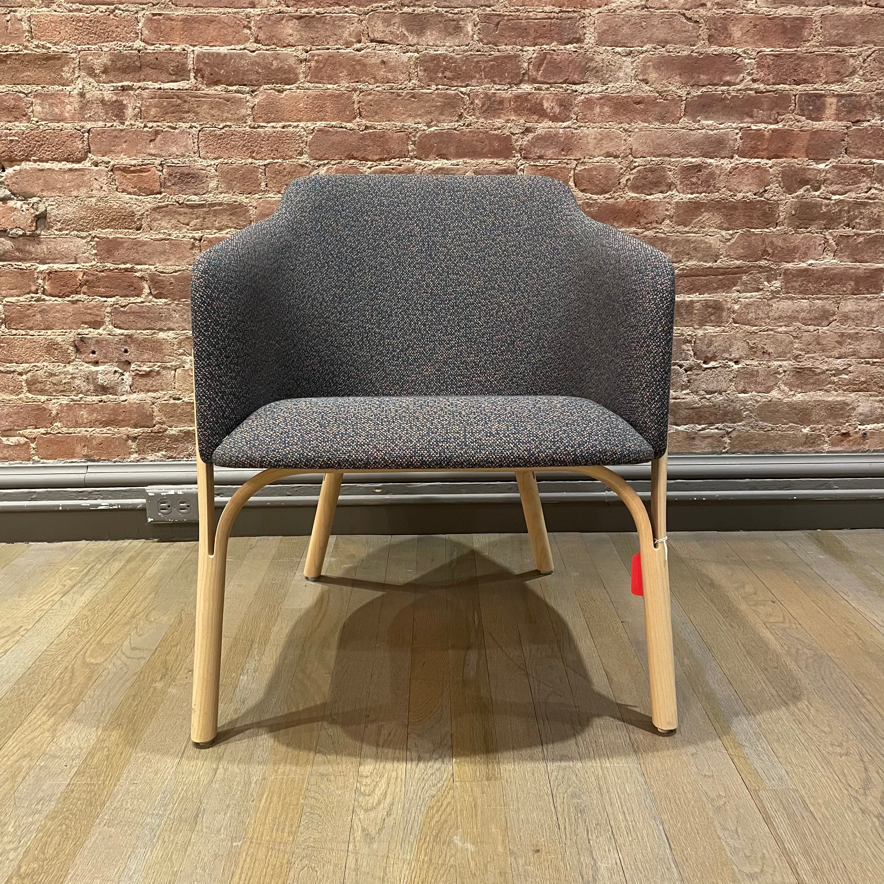 The Lounge Chair Split - Sale by TON features a textured gray fabric seat and light wooden legs, crafted using manual wood bending techniques, set against a wooden floor with a brick wall backdrop.