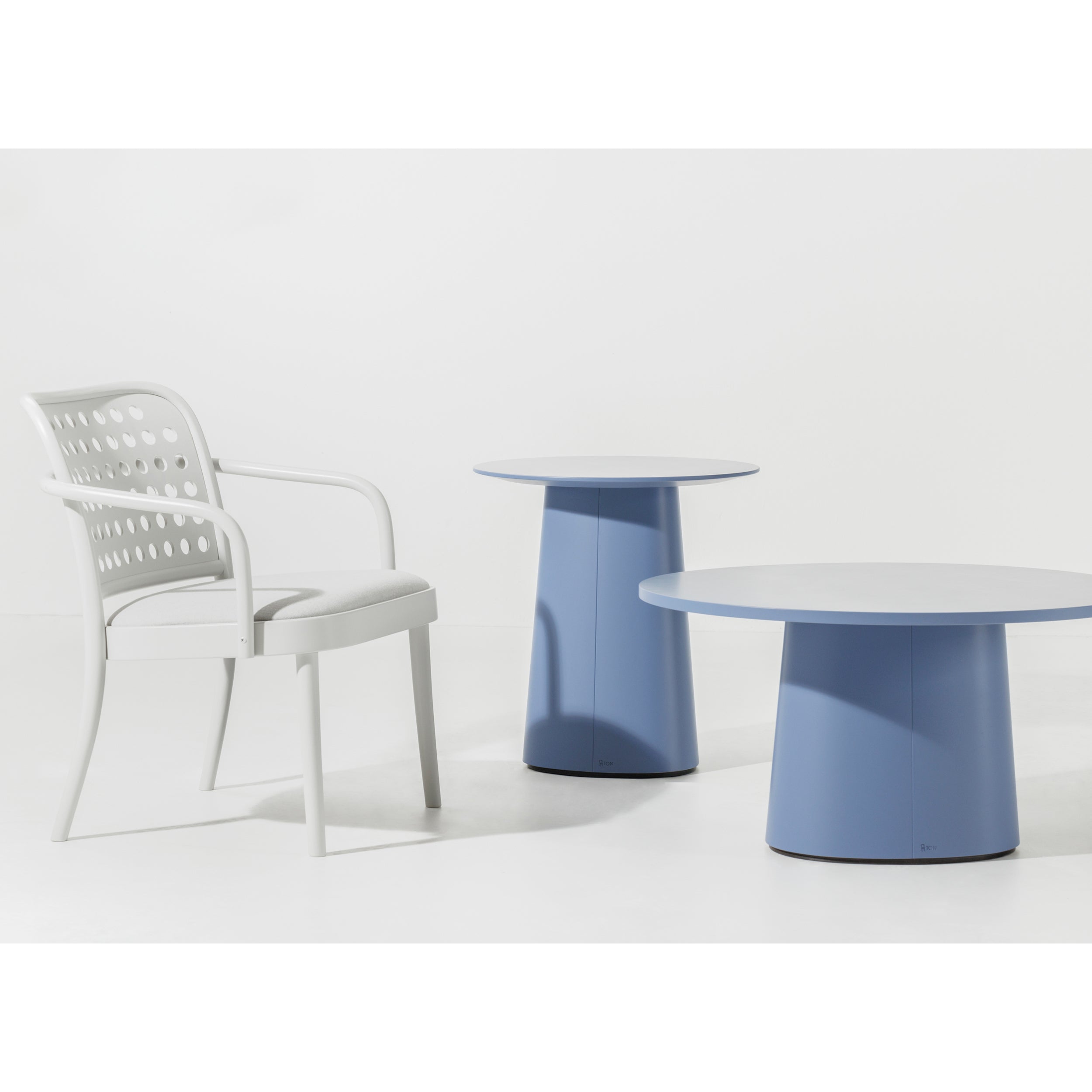 In a minimalist scene, the white chair boasts armrests and a perforated backrest. Its paired with two TON P.O.V. Coffee Table 473 models in blue, each at varying heights, all against a plain white background for an organic design touch with subtle color options.