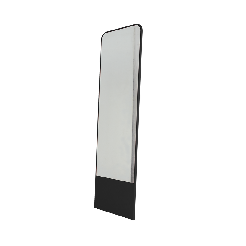 The Friedrich Mirror by Objekte unserer Tage leans slightly to the side on a white background, showcasing its minimalist design with a tall, rectangular shape and black frame with rounded top corners—ideal for a contemporary living space.