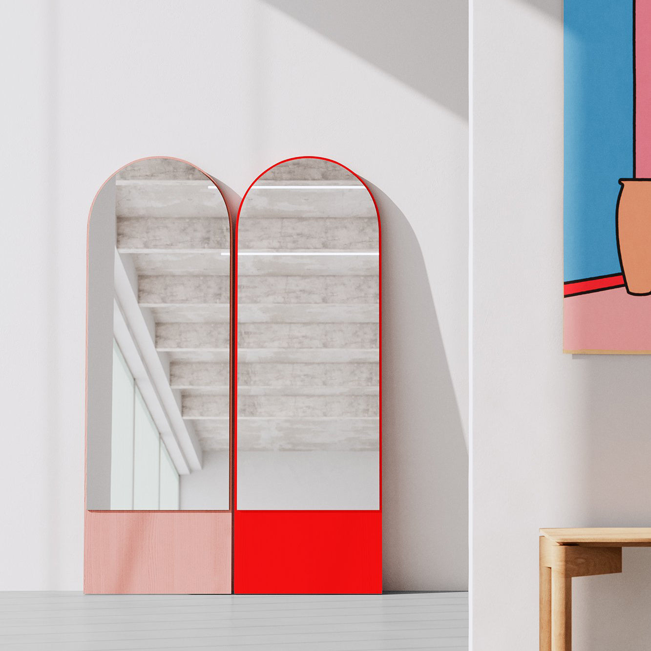 Two FRIEDRICH 21 mirrors by Objekte unserer Tage stand side by side in a bright room, framed in lacquered ash wood. One reflects a minimalist interior with large windows, with glimpses of colorful abstract art and a wooden bench.