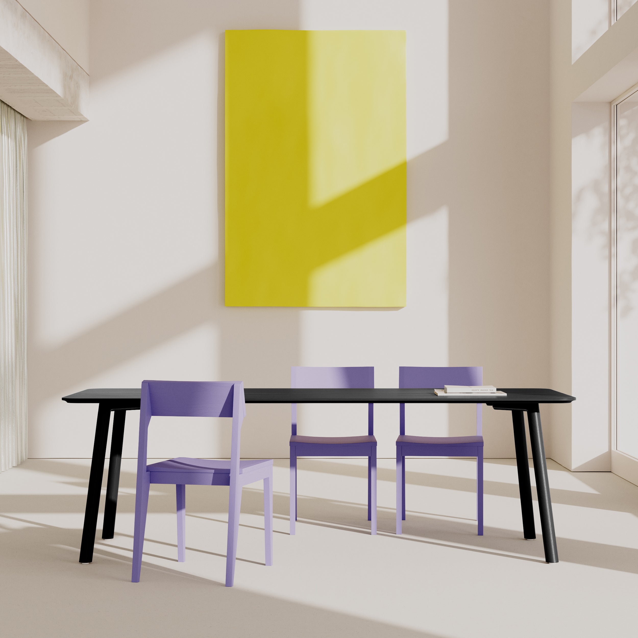 A minimalist interior showcases the Meyer Color Table by Objekte unserer Tage, a long black dining table with an ash wood veneer. Its accompanied by three purple chairs and a large yellow rectangular artwork on the wall, with natural light casting geometric shadows for a serene ambiance.