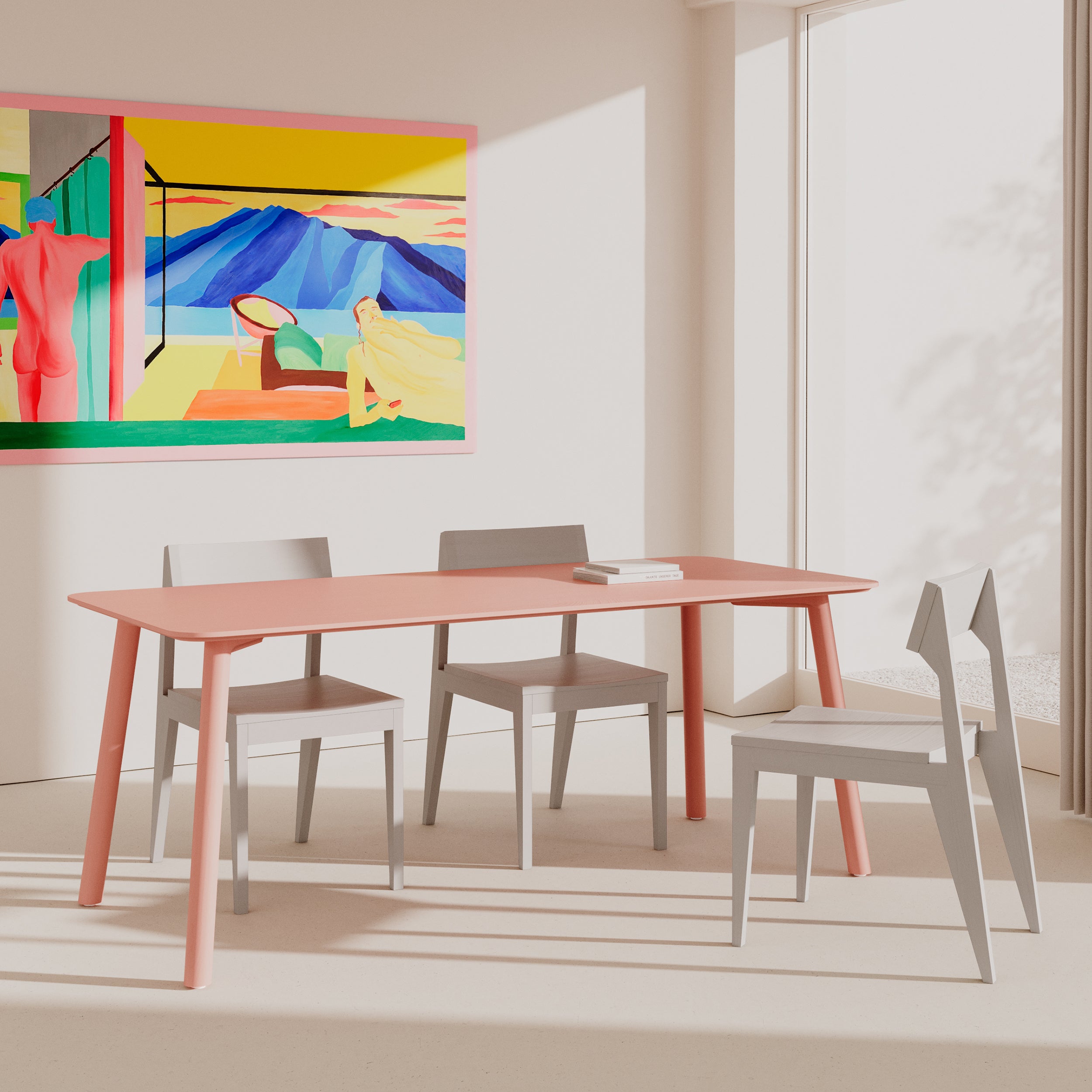 A modern dining room showcases the Meyer Color Table in pale pink by Objekte unserer Tage, surrounded by four gray chairs. Sunlight pours through large windows, casting shadows on the floor. A vibrant painting of abstract figures and landscapes brightens the wall.