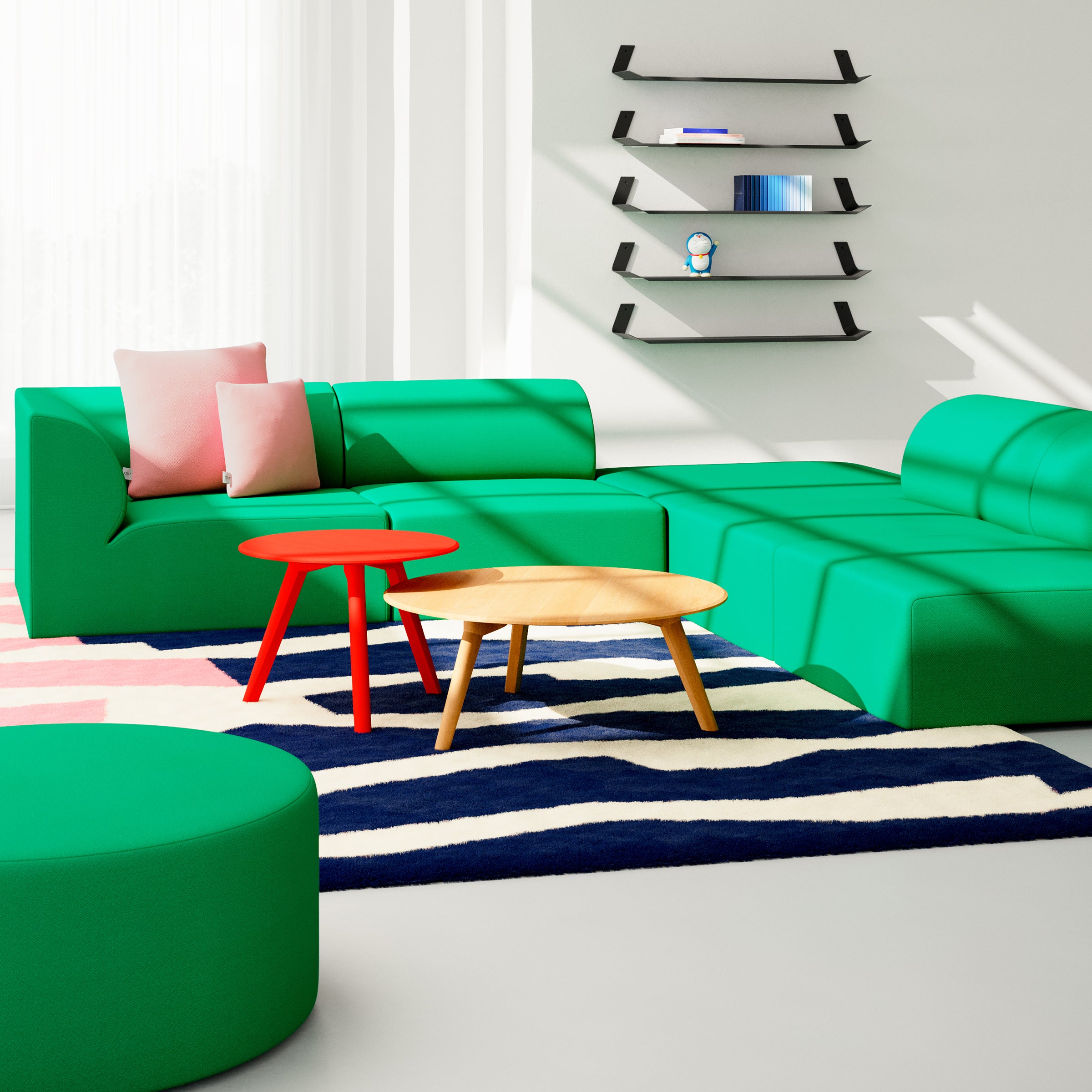 A modern living room highlights the green Weber Modular Sofa by Objekte unserer Tage, paired with round wooden and red tables on a geometric-patterned rug. Black wall-mounted shelves feature decor accents near sheer white curtains that allow natural light to illuminate the space.