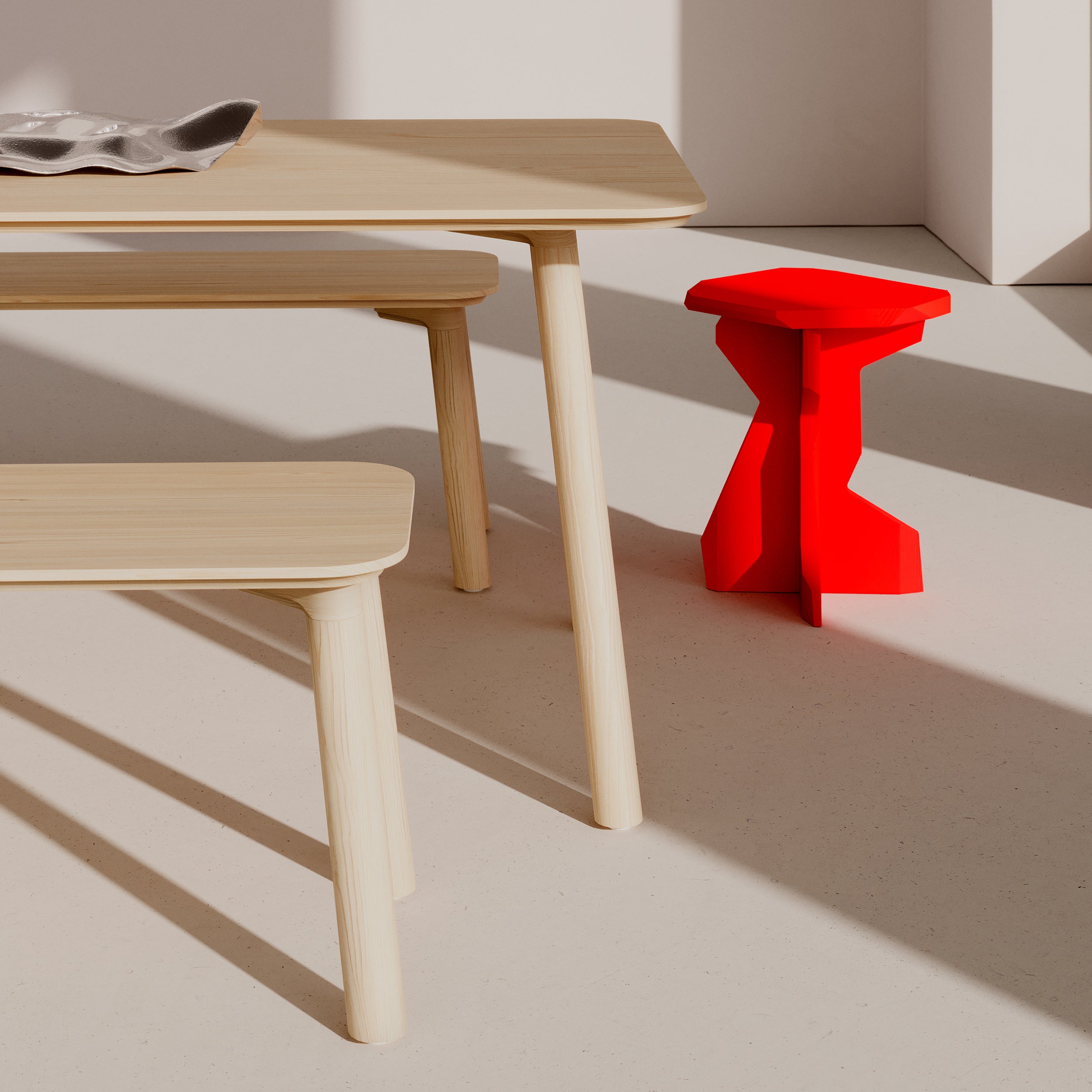 A minimalist room with light wood furniture, such as a solid wood table and bench, features a Meyer 23 Table by Objekte unserer Tage. Sunlight casts shadows on the beige floor, highlighting sustainable beauty while the geometrically shaped stool adds a pop of color.