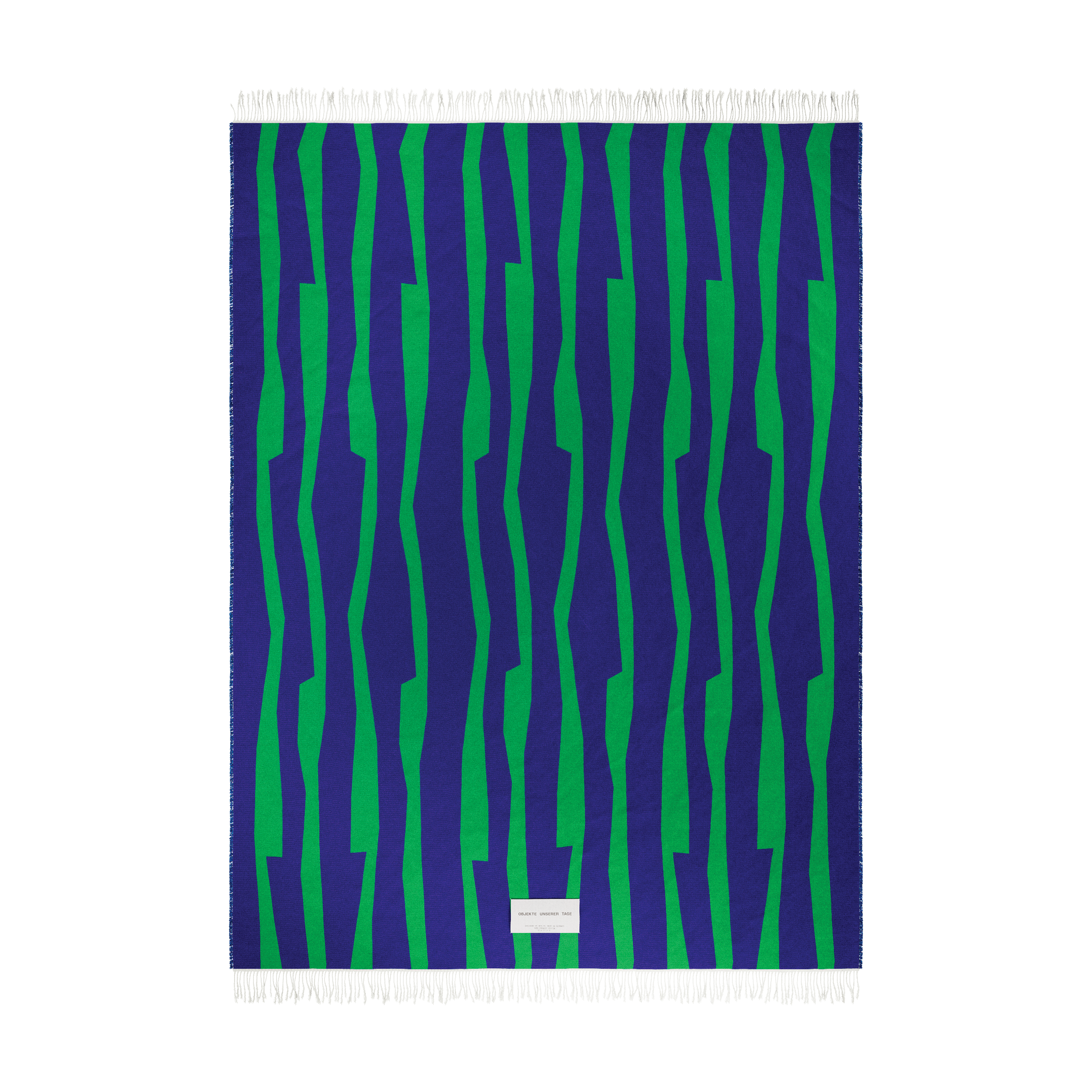 Presenting the SEIDEL Throw by Objekte unserer Tage: a rectangular organic cotton textile featuring green and dark blue vertical zigzag patterns with short fringes on the top and bottom, plus a small white label near the bottom center.