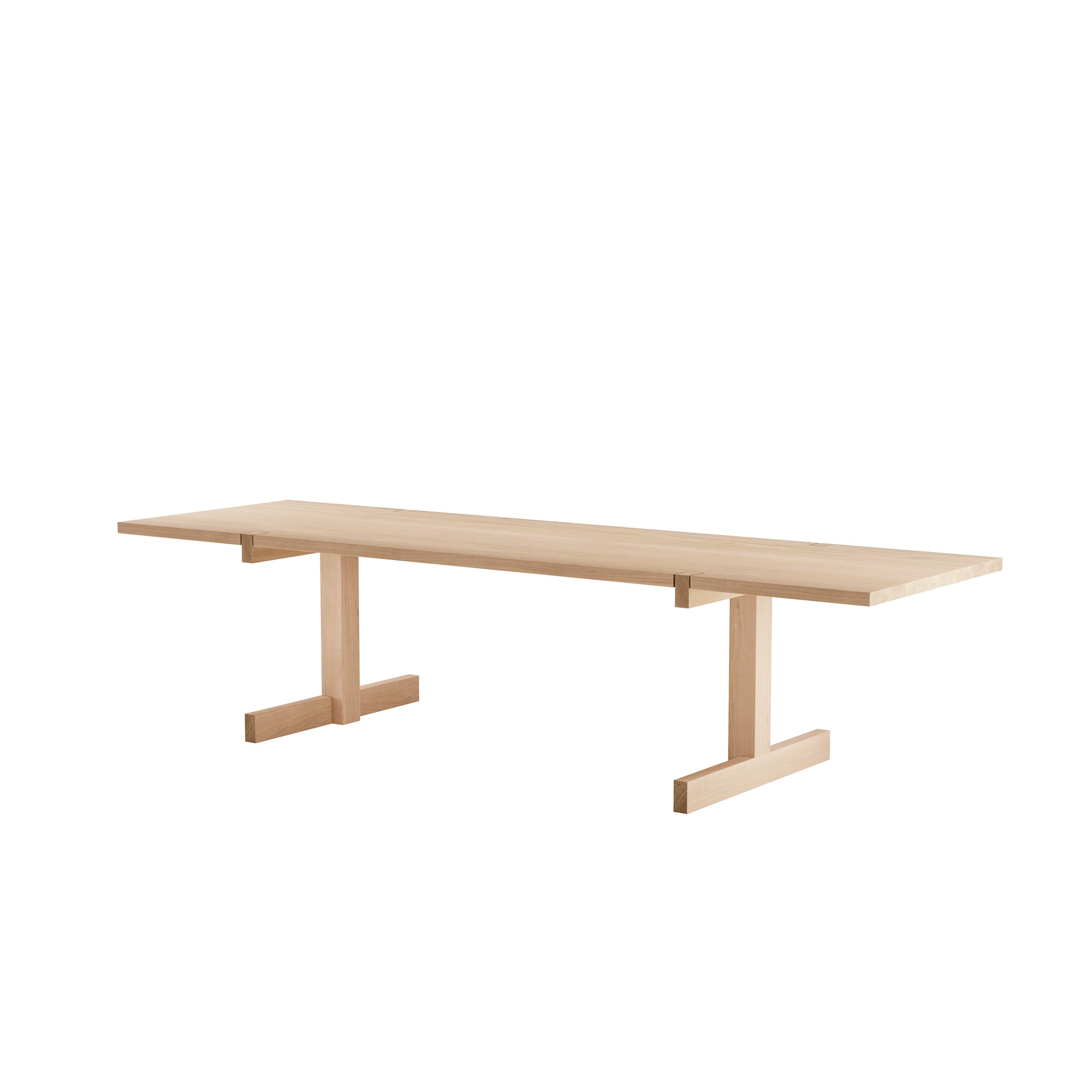 The Richter Table by Objekte unserer Tage is a minimalist wooden dining table featuring a light natural finish, handcrafted with sustainable forestry practices. It has a flat rectangular top and sturdy T-shaped legs, embodying simple elegance.
