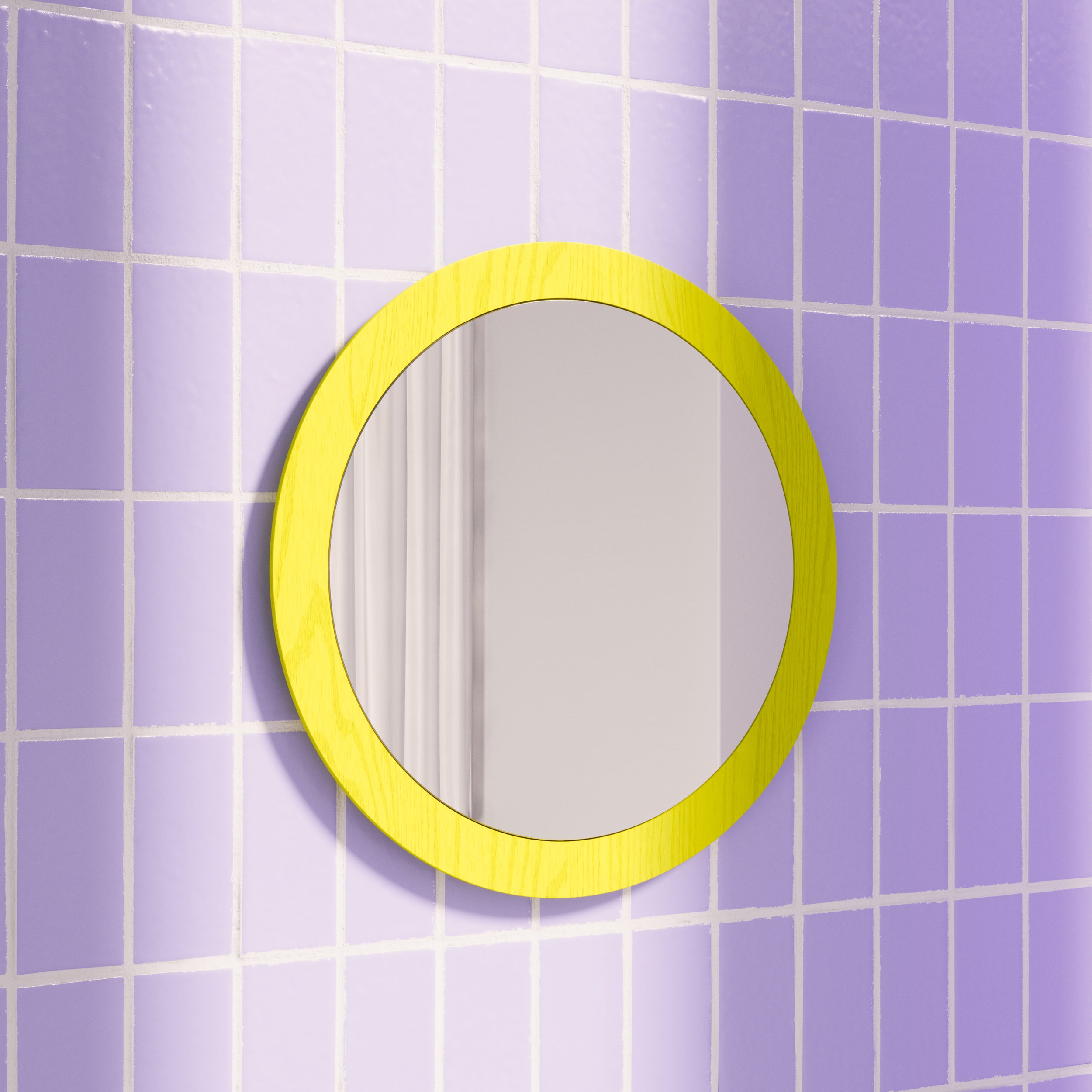 The Lorenz Mirror by Objekte unserer Tage, with its bright yellow frame, is mounted on a wall with lilac grid tiles. Its design reflects a subtle portion of the glossy tiles, offering a modern and clean aesthetic.