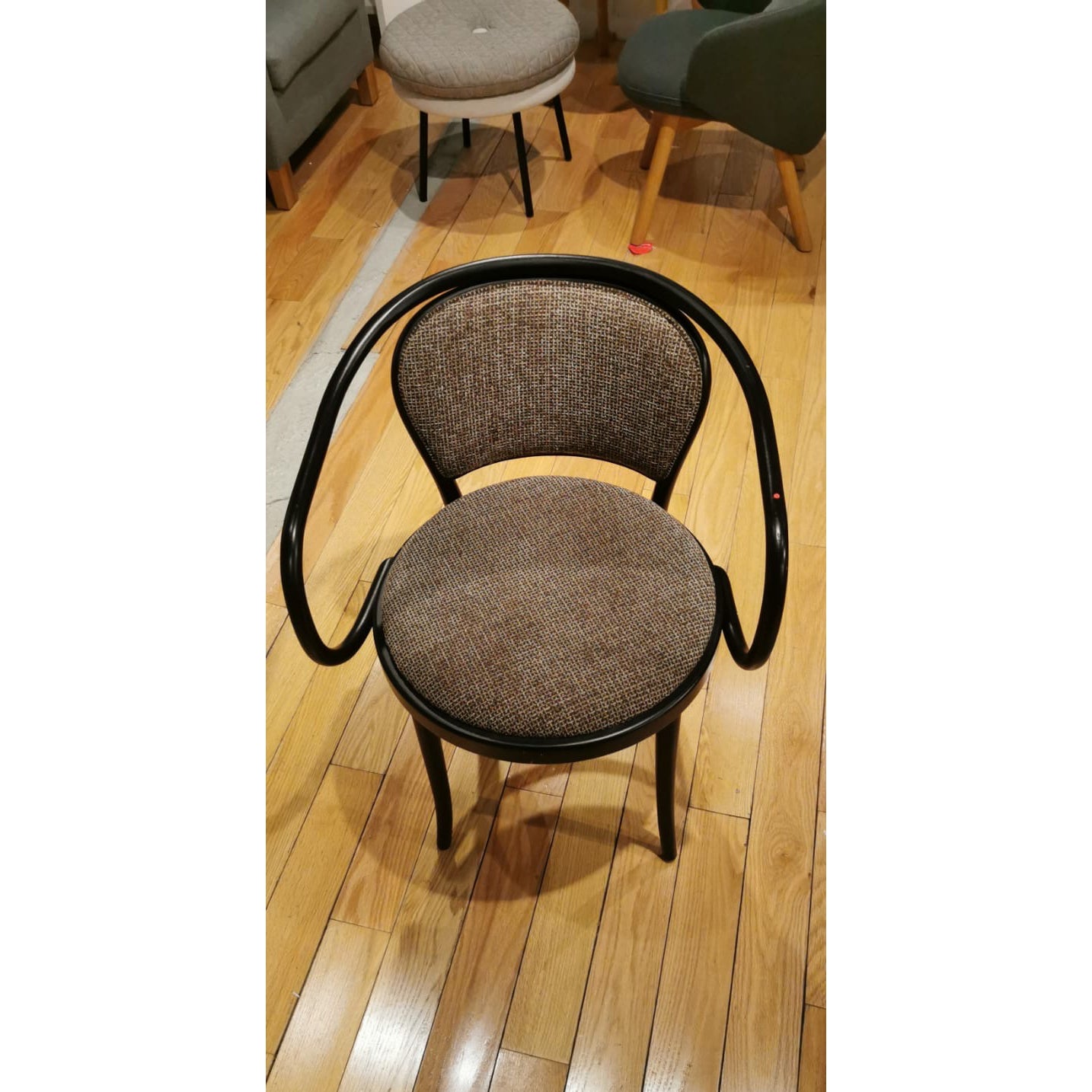 Armchair 33 - Sale by TON: A modern wooden design with an open backrest and armrests, plus a brown cushioned seat and back. It sits on a polished hardwood floor among other furniture, showcasing classic TON elegance.